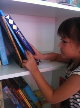 Ella picking out a book at 語言家 Language Plus Living Space